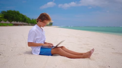 Un étudiant est engagé dans l'auto-éducation assis sur la plage sur fond de turquoise
