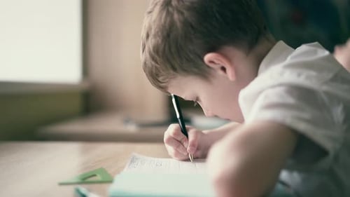 Boy Writing on Paper at School Desk