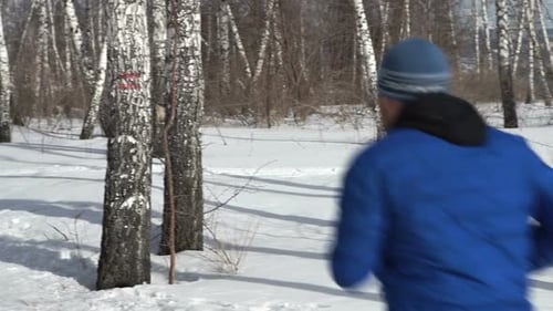 Back View Of Man Is Running Through The Forest In Winter