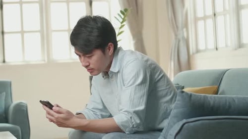 Young Adult Using Phone on Couch Indoors