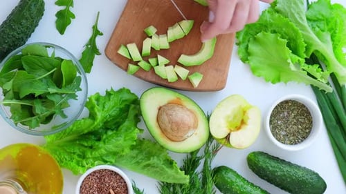 Woman Cooking Salad of Fresh Green Vegetables and Herbs