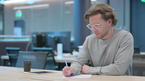 Man Writing at Desk in Modern Office