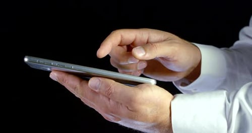 Nahaufnahme männlicher Hände, die einen Tablet-Computer halten und über den Touchscreen im Internet surfen