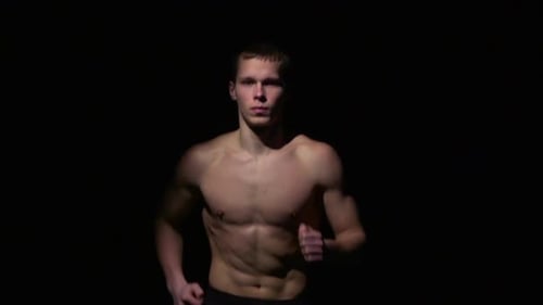 Shirtless Muscular Man Jogging Against Black Background