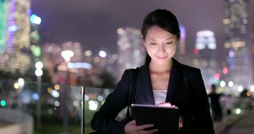Woman Using Tablet in City at Night