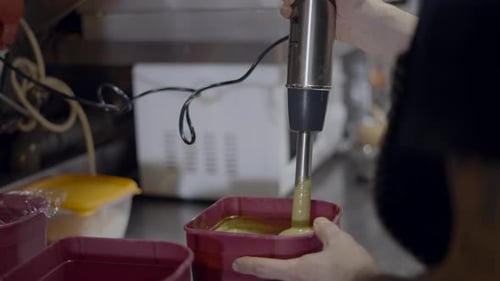 Close Side View of Immersion Blender Mixing Sauce in Plastic Container