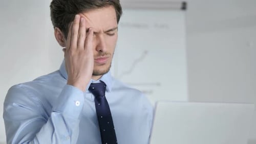 Close Up of Young Businessman with Headache Working in Office