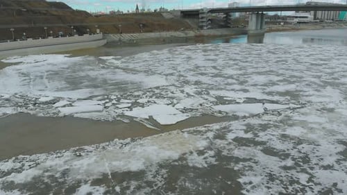 Río congelado bajo un puente gris contra los edificios de la ciudad