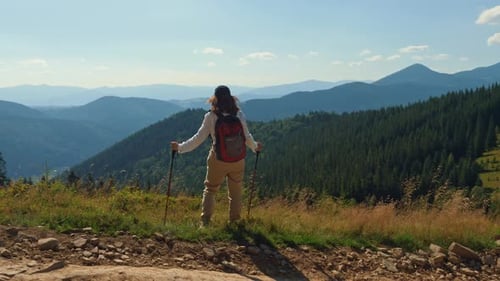 Woman with Trekking Poles Standing on the Top of the Mountain