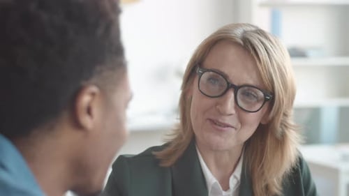 Lächelnde Personalmanagerin im Gespräch mit junger afroamerikanischer Mitarbeiterin im Büro