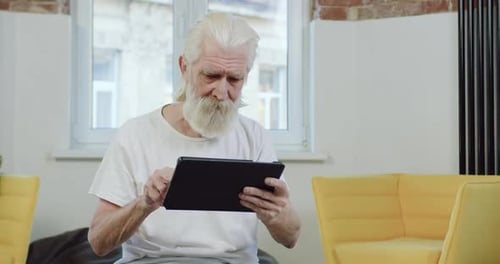 Senior Man Using Tablet Indoors at Home