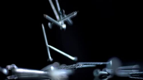 Screws Falling in Slow Motion on Black Surface