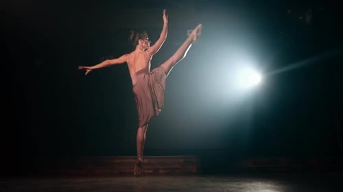 Graceful ballerina in beige dress dancing elements of classical or modern ballet