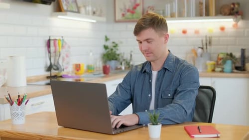 Man Uses Laptop at Kitchen Table