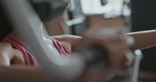 Closeup Portrait of Young Woman Doing Workout on Exercise Machine in Gym