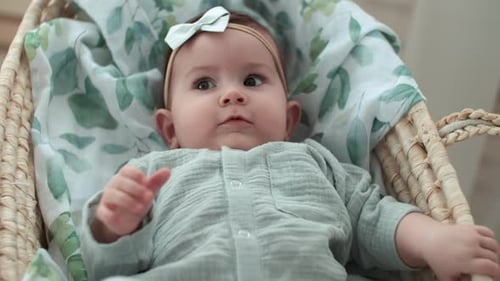 Cute Baby Lies in Woven Bassinet Awake