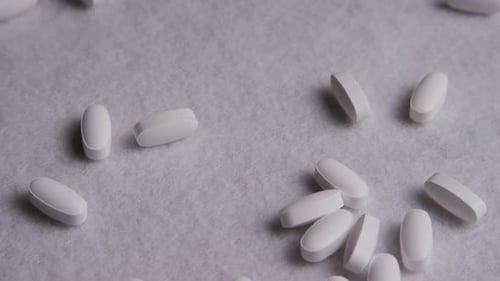 White Pills Scattered on Light Gray Surface