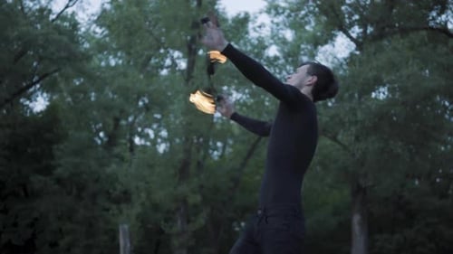 Young Man Spins and Breathes Fire Outdoors