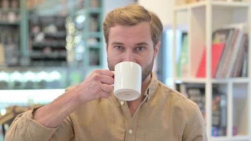 Bearded Man Drinks From a White Mug