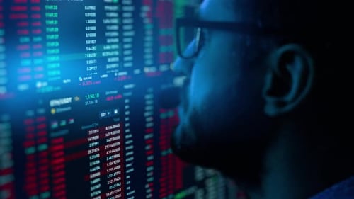 Man Analyzes Financial Data on Screen at Night