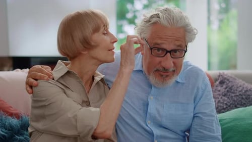 Loving Senior Couple Sitting Together on Couch Indoors