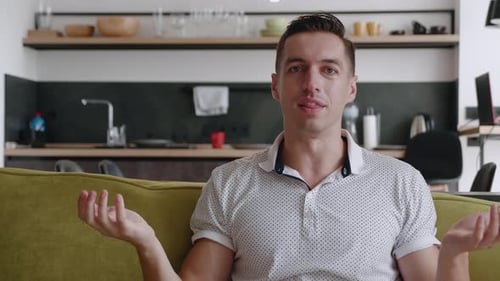 Enthusiastic man talking to the camera on couch