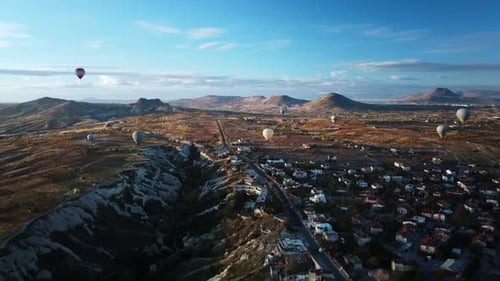 Hot Air Balloons are Flying Over Limestone Gorge and Town Built Next to It in Turkey