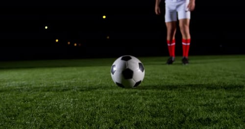 Athlete Kicks Soccer Ball on Field at Night