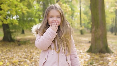 Cute Little Caucasian Girl Blows a Kiss to the Camera with a Smile in a Park