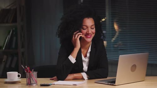 Woman Talking on Phone and Typing on Laptop
