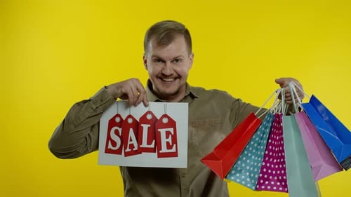 Happy Man Showing Sale Word Inscription, Smiling, Looking Satisfied with Low Prices, Slow Motion