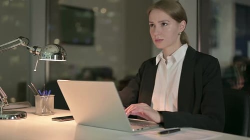 Woman Working Late at Laptop in Urban Office