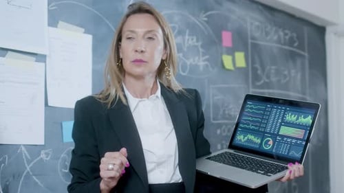 Businesswoman Presents Data at Chalkboard with Laptop