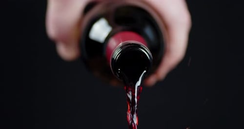 A Man's Hand Holds a Bottle of Pouring Wine.