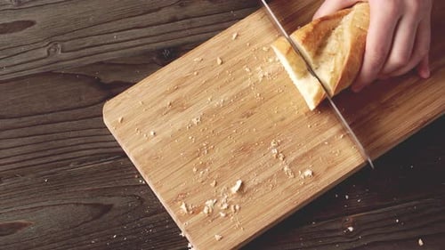 Hands of a Woman Cutting Bread Loaf on Wooden Cutting Board