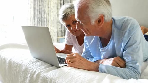 Senior Couple Using Laptop Together in Bedroom