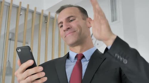 Man Celebrates Good News on Smartphone in Office