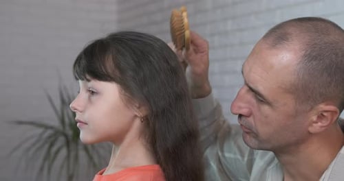 Loving Father Brushing Daughter's Hair at Home