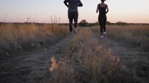 Couple Running Through Field at Sunset