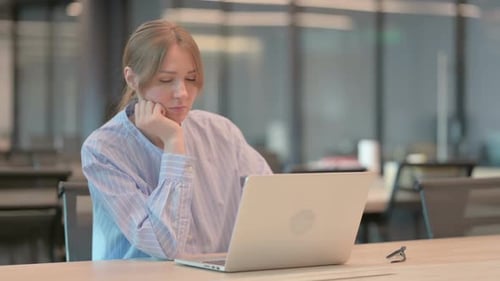 Tired Young Woman Taking Nap While Sitting in Office with Laptop