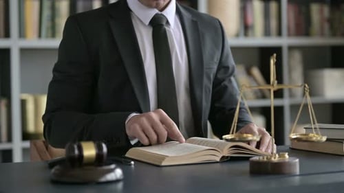 Close Up Shoot of Lawyer Hand Reading Book on Court Room Table