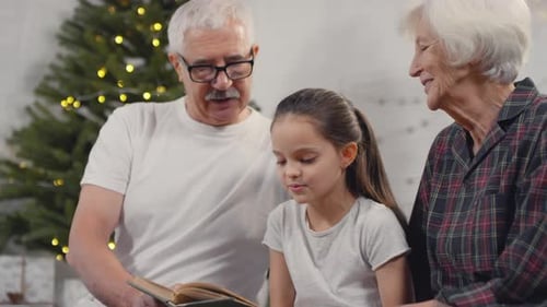 Grandparents Reading a Christmas Story to Granddaughter