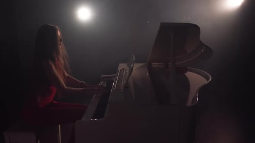 Woman Playing Grand Piano in Dramatic Lighting