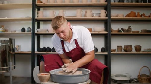 Man Shaping Clay on Pottery Wheel in Studio