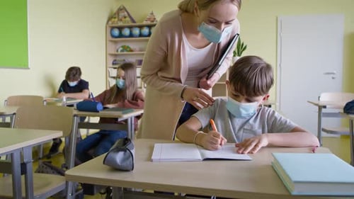 Masked Students Working at Desks in Classroom
