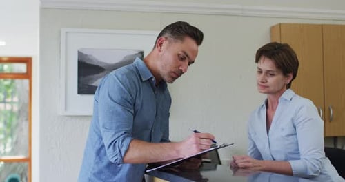 Caucasian man talking and signing documents at reception at modern dental clinic