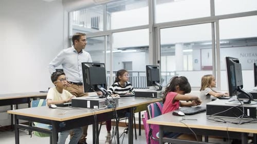 Profesor de informática observa a los alumnos haciendo sus tareas