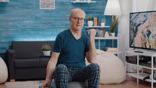 Man Lifts Dumbbells At Home on Exercise Ball