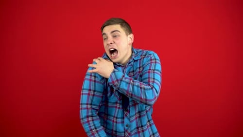 Young Adult with Shoulder Pain on Red Background