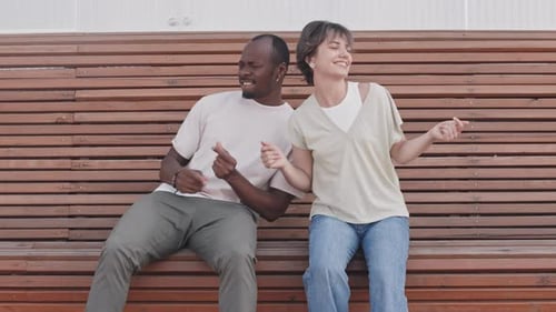 Friends Dancing Together on Outdoor Bench